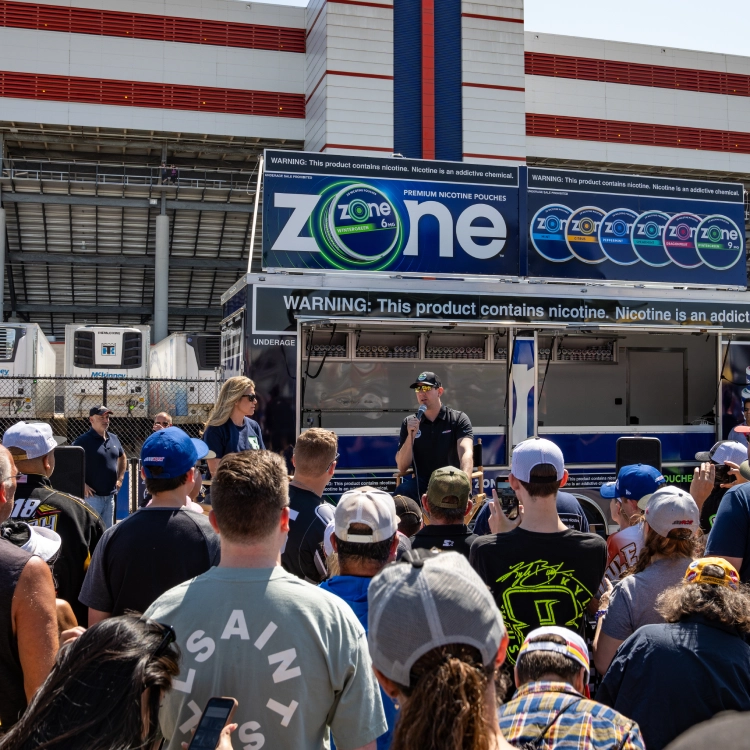 Kyle Busch speaking in front of a crowd at a a Zone kiosk