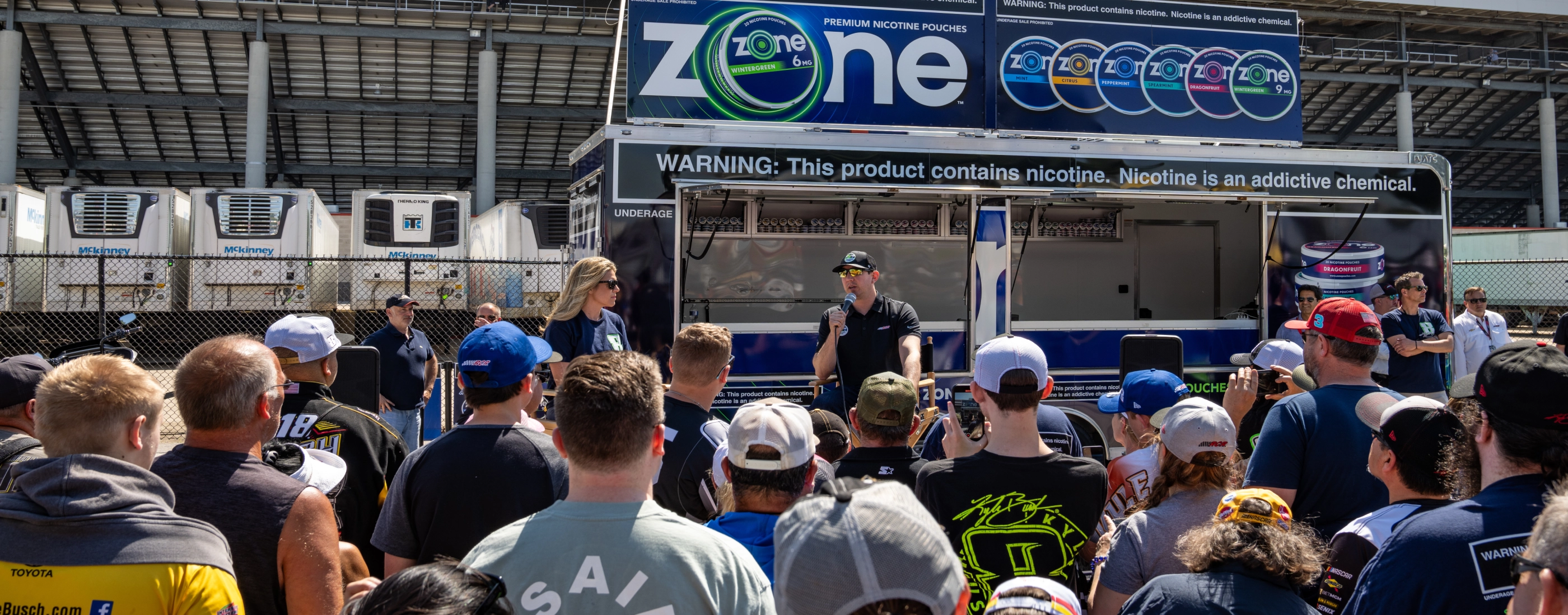 Kyle Busch speaking in front of a crowd at a a Zone kiosk